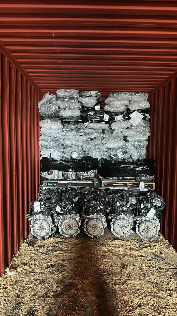 Red shipping container with engines and wrapped components arranged in layers